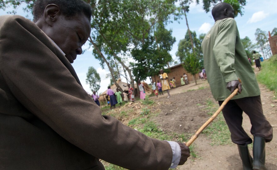 Oromdi Yallo Lambert leads his blind father, Fabiano Olur, who lost his sight to river blindness, in Nebbi district, Uganda.
