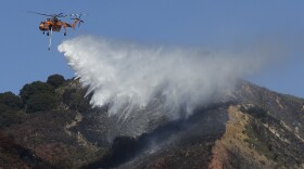 A helicopter drops water over a part of the Oakland Hills in Oakland, Calif., Tuesday, Sept. 26, 2017. 