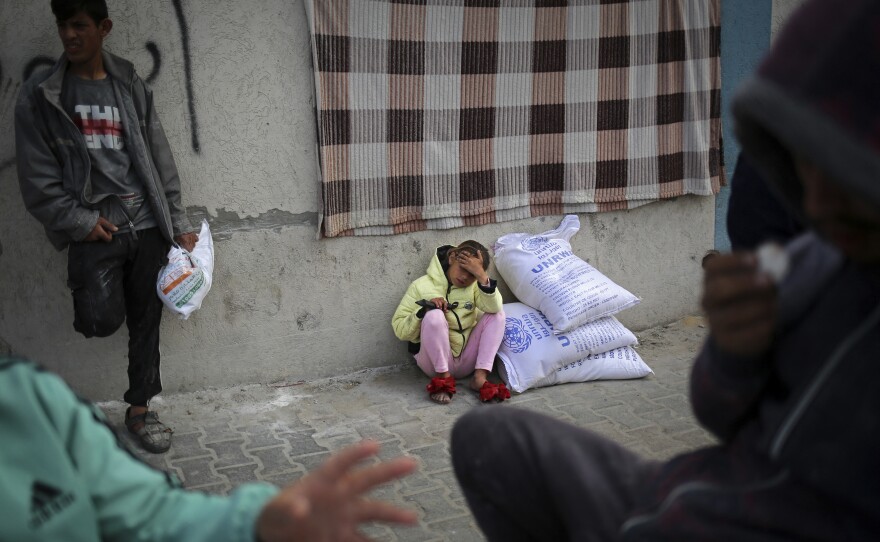 A displaced Palestinian girl sits next to sacks of humanitarian aid at the distribution center of the United Nations Relief and Works Agency for Palestine Refugees (UNRWA), in Rafah in the southern Gaza Strip on March 3.