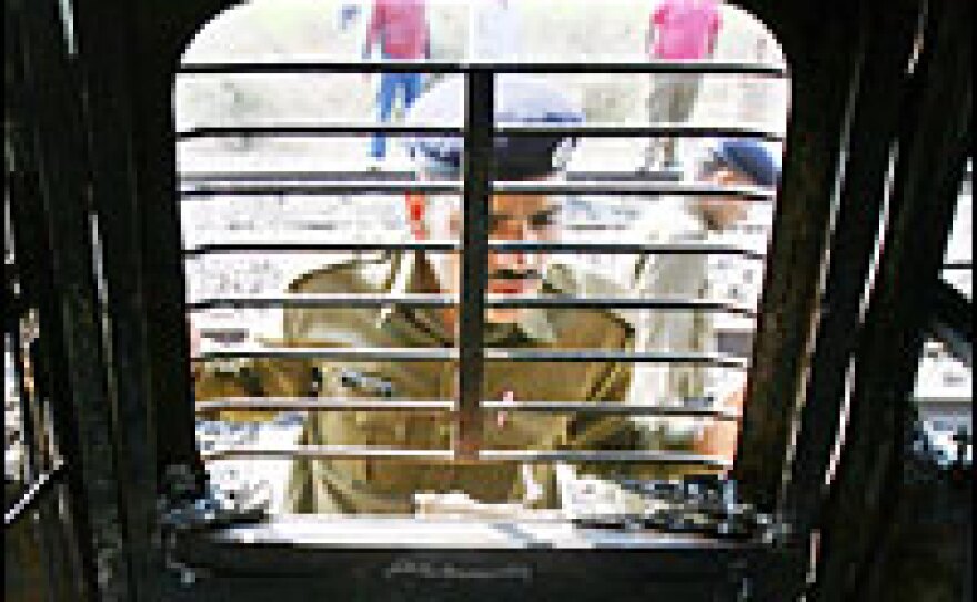 An Indian security officer peers into the charred carriage of an Indian train that exploded Feb. 19.