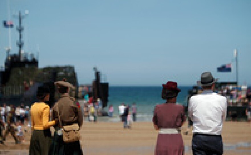 People wearing clothes in the style of the World War II era look toward the sea Friday on the beach of Arromanches, western France. Ceremonies for the 70th anniversary of D-Day included an artistic re-enactment of the coastal assault.