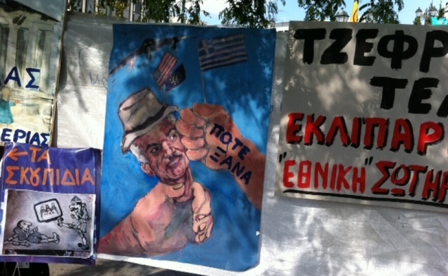 <p>A poster depicts Greek Prime Minister George Papandreou as an American puppet. The words on the hand hitting Papandreou's face are "never again".</p>