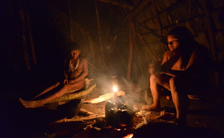 Two Waorani women stare at fire.
