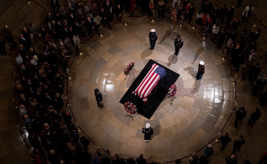 Members of the public view the casket containing former President George H.W. Bush's remains as he lies in state in the U.S. Capitol Rotunda on Monday night.