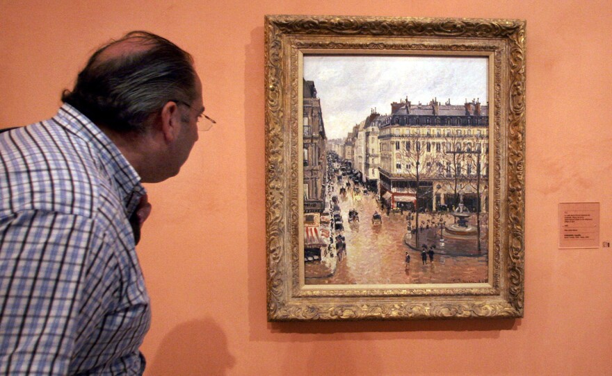 This May 12, 2005 file photo shows an unidentified visitor viewing the Impressionist painting called "Rue St.-Honore, Apres-Midi, Effet de Pluie" painted in 1897 by Camille Pissarro, on display in the Thyssen-Bornemisza Museum in Madrid. Lilly Cassirer surrendered her family's priceless Camille Pissarro painting to the Nazis in exchange for safe passage out of Germany during the Holocaust. 