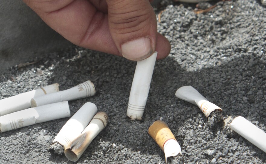 A smoker snuffs out a cigarette at the Capitol in Sacramento, Calif.
