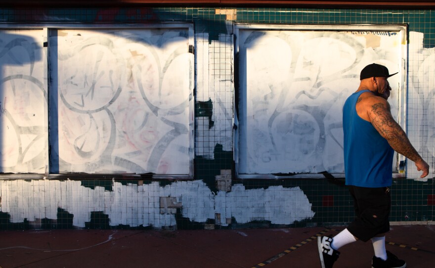 A man walks past a storefront that has been grafittied and painted over on University Avenue in North Park on Nov. 15, 2022.