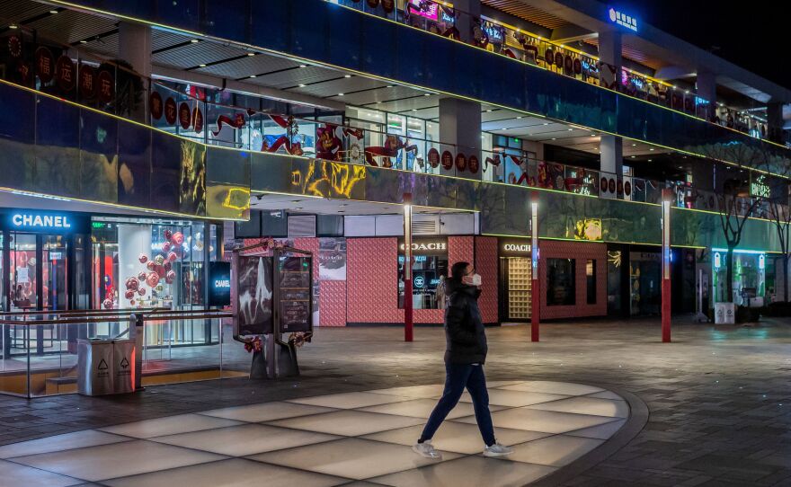 A man wearing a protective face mask walks at a nearly empty shopping mall in Beijing on Feb. 27. Business activity in China has all but halted, with entire cities under quarantine and industries forced to lay off workers.