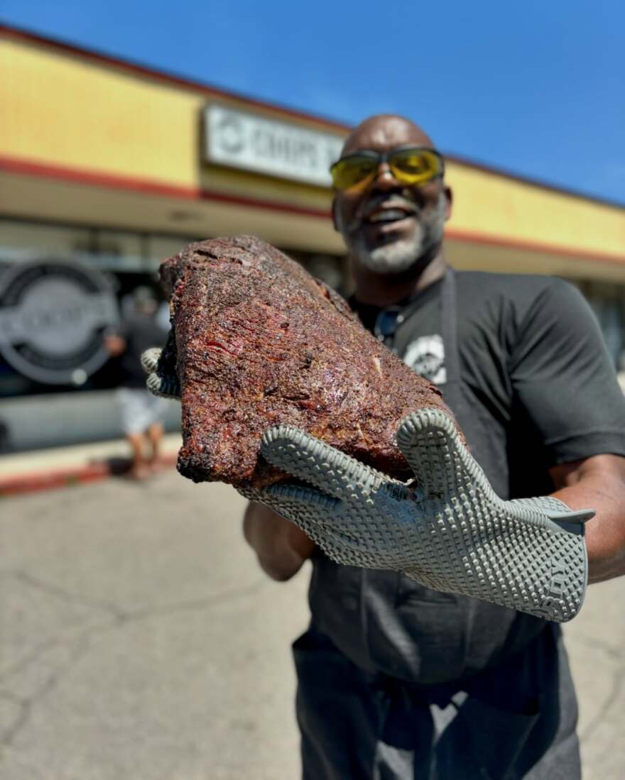 Bradrick Cooper holding up some of his melt-in-your-mouth brisket that cooks in brick oven pits for hours. Undated photo.