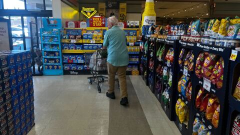 Pictured, a man walking out of a grocery store pushing a shopping cart on July 30, 2025. 