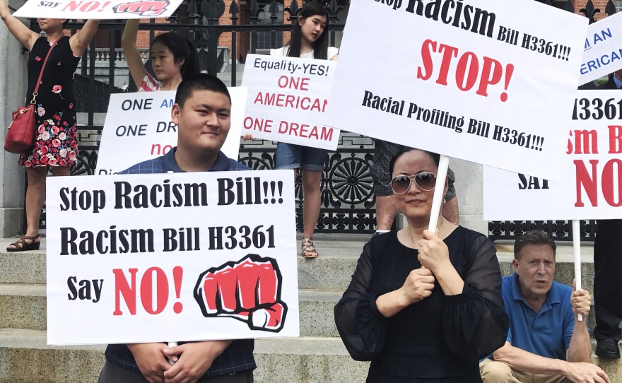Linglan Zhang (right) of Lexington, Mass., holds a picket sign next to her son, Sean (left), and boyfriend, David Kates (right).
