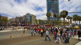 Waves of Comic-Con attendees cross the street headed towards the convention center. 