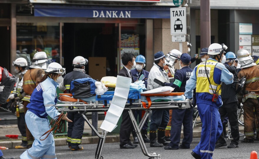 First responders carry a stretcher after a deadly fire at an eight-story building in a major business, shopping and entertainment district in Osaka on Friday.