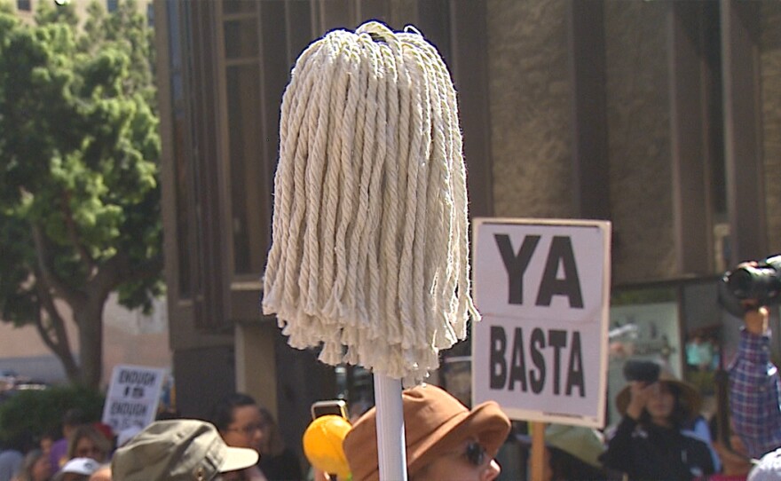A protestor holds up a mop at a march to raise awareness about assault in the workplace against women who work as janitors, March 8, 2016.
