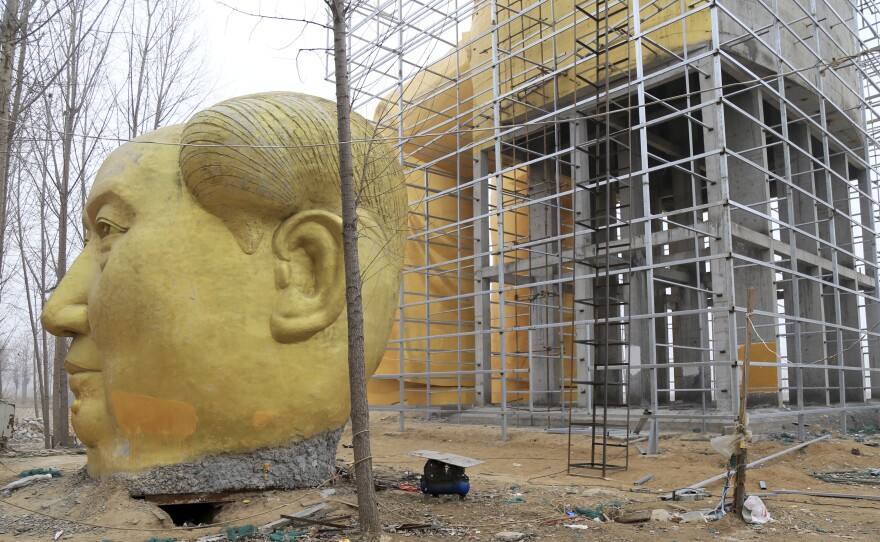 Another head in Mao's likeness is placed on the ground next to the giant statue of Mao.