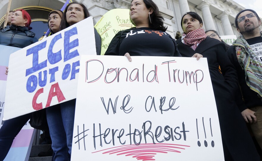 In this Jan. 25, 2017 file photo protesters hold signs as they listen to speakers at a rally outside of City Hall in San Francisco, Calif. 