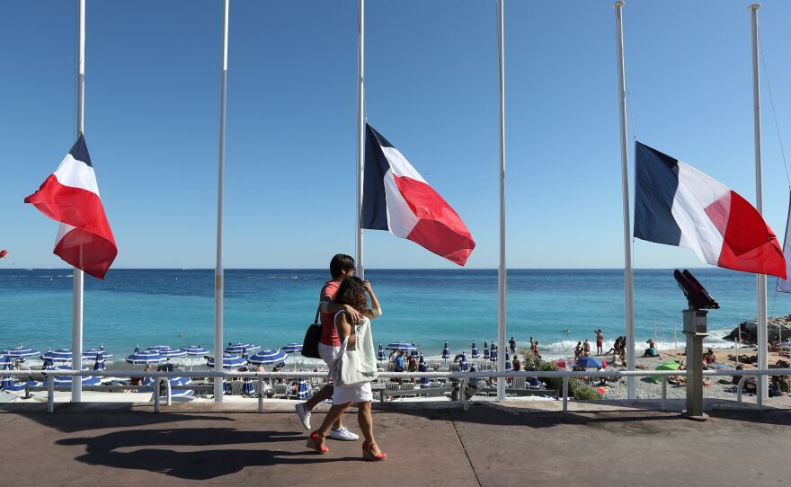 French flags are seen lowered at half-staff in Nice on July 16. The truck attack on July 14 killed 84 people. "I felt coming to celebrate on holiday and people are in mourning didn't seem right," one vacationer says. "But I'm glad I came."