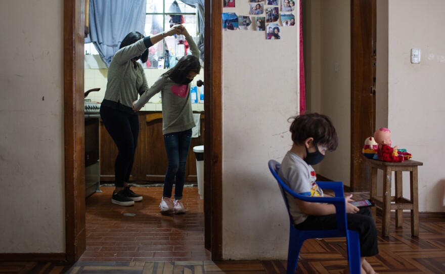 Barreto, left, dances with her granddaughter in the kitchen. She lives with her son, daughter-in-law and their two kids. Even though the family is having a tough time, Barreto says she tries to look for ways to be happy. "When I cook <em>cachapas</em>, I turn on my Venezuelan music and start cooking, dancing and remembering my country."