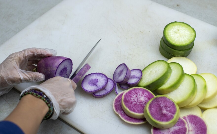 A purple daikon radish grown at Ollin Farms in Longmont, Colo., and other vegetables are prepared to be served at a meeting to discuss support for small Colorado farmers in December.