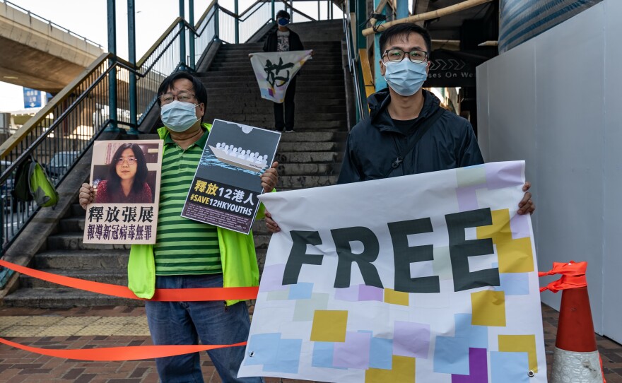 Pro-democracy activists hold placards in support of 12 Hong Kong residents detained in mainland China and former lawyer Zhang Zhan outside the Liaison Office of the Central People's Government on Dec. 28 in Hong Kong. They protested as Zhang and the 12 residents were due in court in Shenzhen, China.