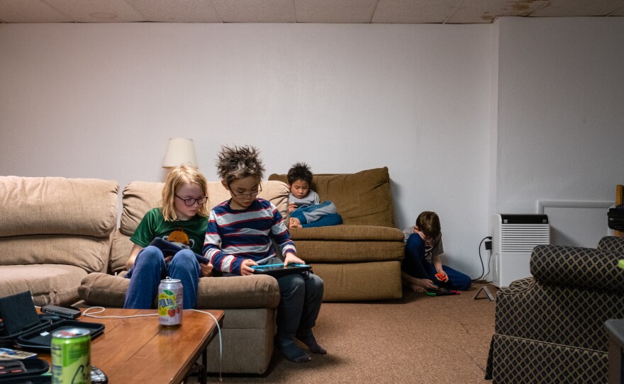 Henry Partain and Henry Pham (front left to right) play on iPads while Hayle Pham and Jack Partain play Nintendo Switch after skiing in Seven Springs, Pa., on Feb.16, 2020.