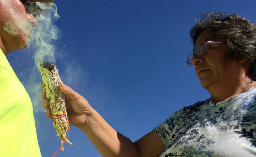 An Indian woman cleanses a volunteer for Aguilas del Desierto with sage smoke, Sept. 17, 2016. 