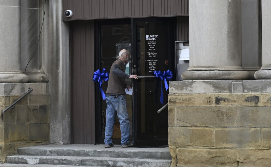 A pedestrian walks into United Bank as ribbons in honor of Sarah Beckstrom adorn the door on Main Street in Webster Springs, W.Va., on Wednesday.