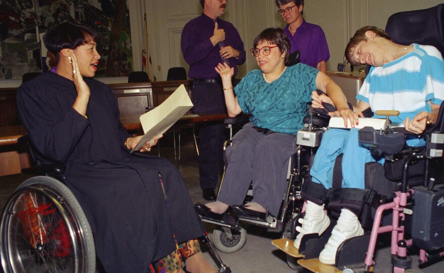 Judy Heumann (center) is given an ovation in June 1993 at her swearing in as U.S. Assistant Secretary for Special Education and Rehabilitative Services in Berkeley, Calif.
