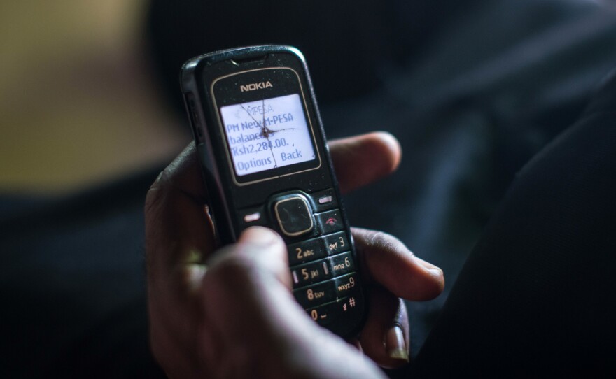 A recipient of cash aid through GiveDirectly's experiment checks his phone to confirm that the latest monthly transfer has been made.