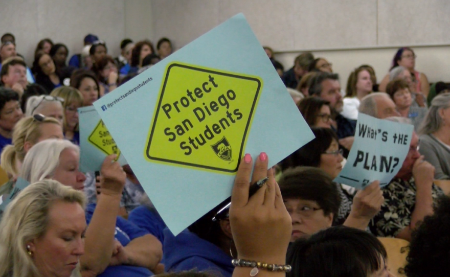 Educators hold signs that read "Protect San Diego Students" and "What's the Plan?" at the San Diego Unified Board of Education meeting, April 25, 2017.