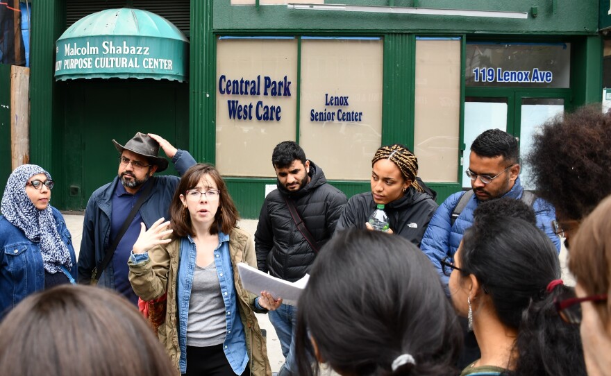 Tour participants listen to guide Katie Merriman (center) outside the Malcolm Shabaaz Mosque as she speaks about the influence of Malcolm X on the Harlem community.