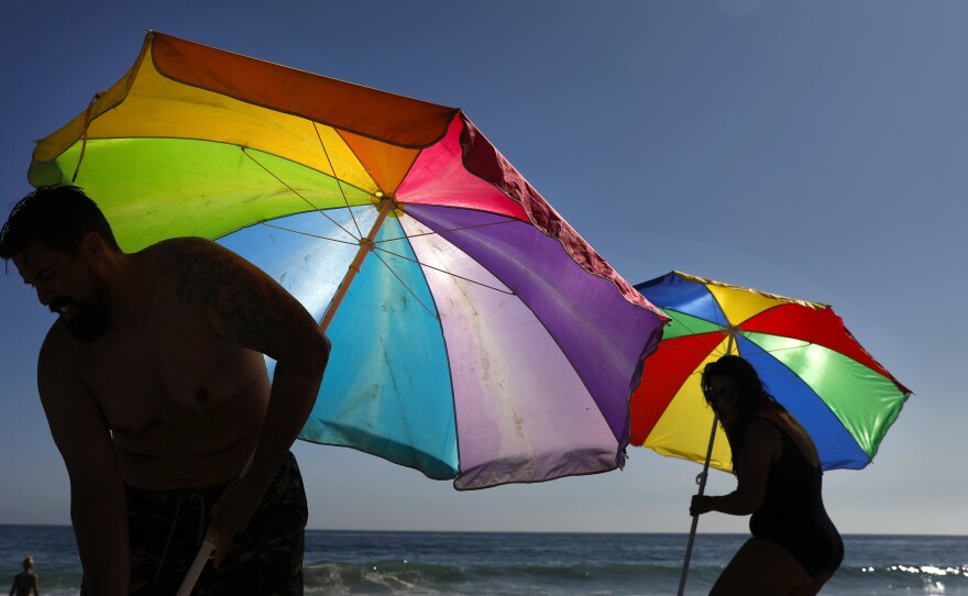 Mario Ramos (left) and wife Tally adjust their umbrellas in Laguna Beach, Calif. The state was among a number of places this summer that experienced their highest temperatures on record.