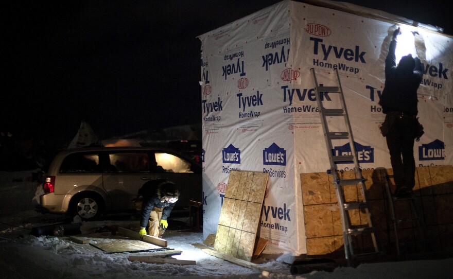 Volunteers wrap insulation around a small box bunkhouse, one of many winterized structures popping up in the three camps along the Cannonball River.