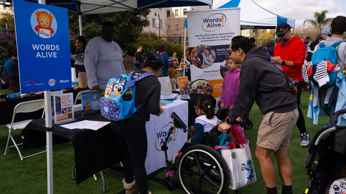 A family visits the Words Alive booth at Be My Neighbor Day across the street from the KPBS station on Saturday, April 6 in San Diego, CA.