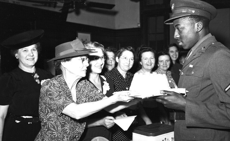 Army PFC Clifton Hall accepts a cake from volunteer Lyda Swenson.