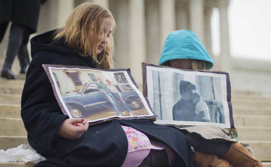 On the steps of the Supreme Court, Helena Roberts, 11, left, and sister Cassie Boyle, 8, hold photographs of their grandmother Hannah Brown, who died a year after losing her job and health care.