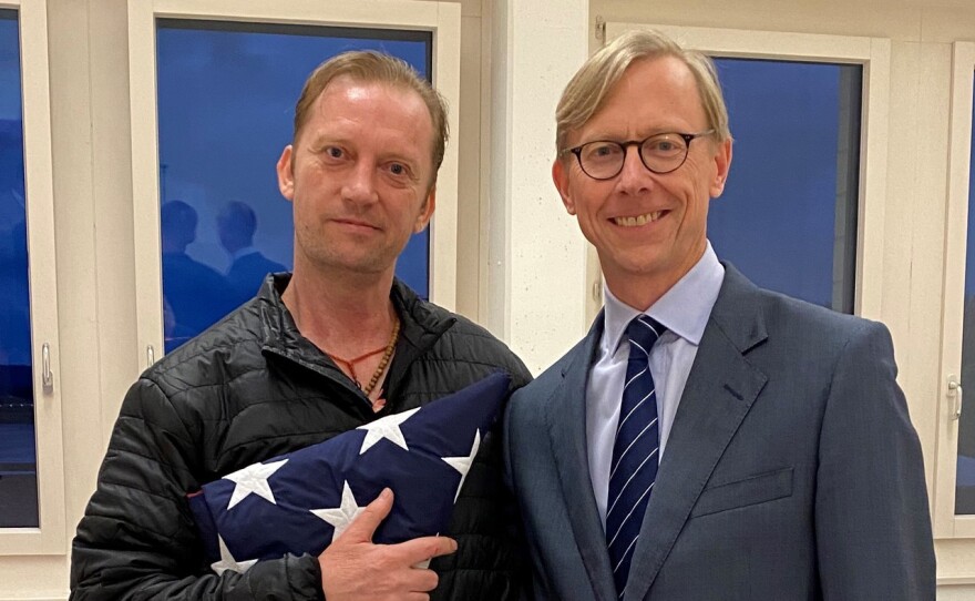 Michael White holding an American flag next to U.S. special envoy for Iran Brian Hook at the Zurich, Switzerland, airport June 4, 2020, after White's release from Iran.