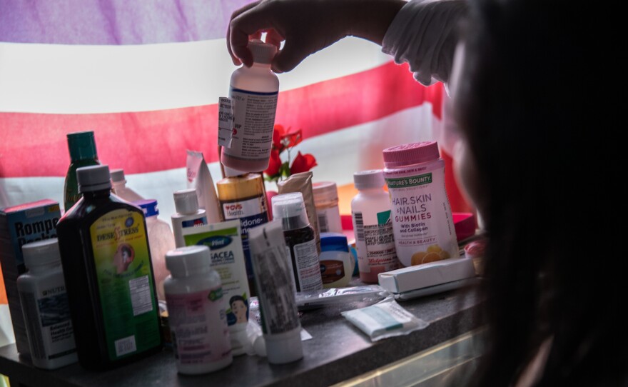A woman recovering from fever linked to COVID-19 checks medications in her home in Mineola, N.Y., this spring.