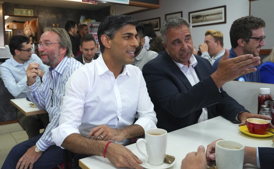 Britain's Prime Minister Rishi Sunak, center, and newly elected Conservative MP Steve Tuckwell, center right, speak at the Rumbling Tum cafe in Uxbridge, after Tuckwell won the Uxbridge and South Ruislip by-election, west London, Friday July 21, 2023.