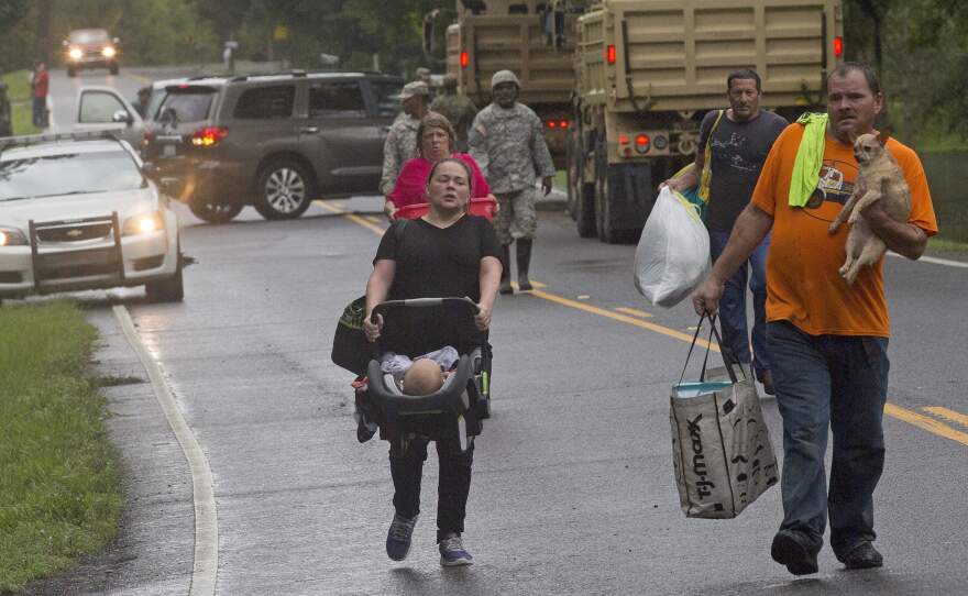 People are evacuated by members of the Louisiana Army National Guard near Walker, La., on Sunday.