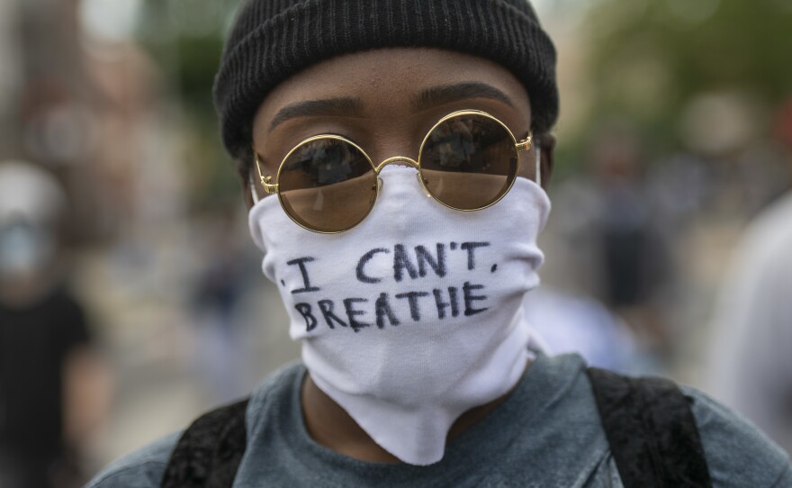 Protests over police treatment of black people have sparked concerns about the spread of COVID-19. Here, a protester marches Monday in Philadelphia with a cloth mask saying, "I can't breathe."