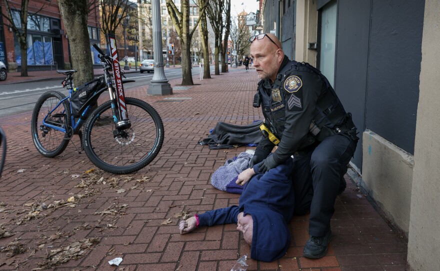 Portland Police Sgt. Jerry Cioeta checks for a pulse after giving a third round of opioid reversal medication to a man found unresponsive in downtown Portland, Ore. The man was revived.