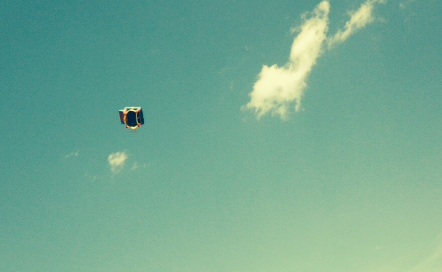 An eyewitness photo shows an inflatable play house being blown high in the air after three children fell out of it, injuring two of them seriously. Proceeds from the licensing of this image are being donated to the kids' families.