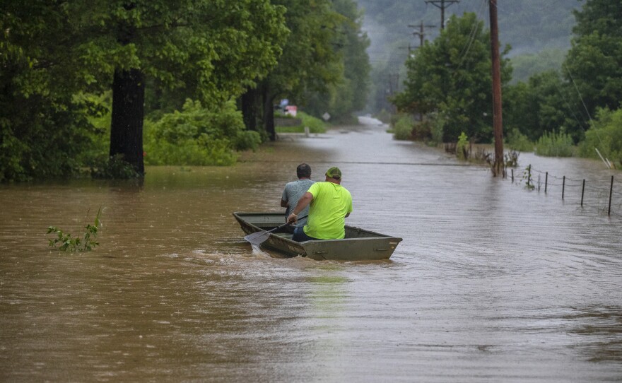 Men ride in a boat along a flooded road in Breathitt County, Ky., on Thursday.