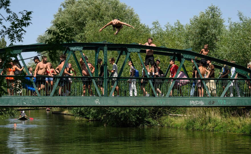 A woman does a backflip into the River Cam in Cambridge, England, on Monday, the first of two days on which temperatures are expected to hit record highs.
