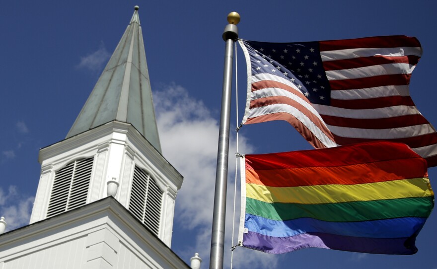 A rainbow gay pride flag flies below the U.S. flag last year in front of the Asbury United Methodist Church in Prairie Village, Kan.