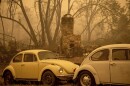 A chimney stands behind cars as the McKinney Fire burns in Klamath National Forest, Calif., on Sunday, July 31, 2022.