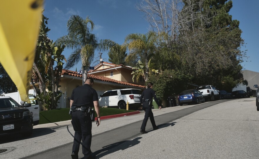 Police block the street to a house where three people were killed and four others wounded in a shooting at a short-term rental home in an upscale Los Angeles neighborhood on Saturday.