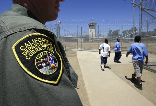 Inmates pass a correctional officer as they leave an exercise yard at the California Medical Facility in Vacaville, Calif., June 20, 2018 . 