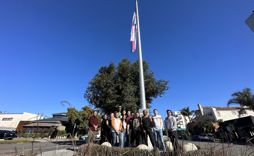 A group of people from the San Diego LGBT Center pose under the Transgender Pride Flag in Hillcrest on Nov. 20, 2023.